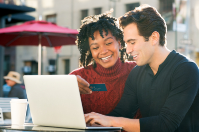 couple paying bills online with laptop and credit card